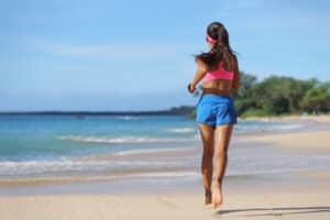 Woman running on the beach with clear, healthy legs from vein disease treatment in Tampa, FL